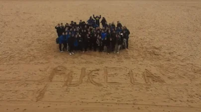 Alumnos del Colegio El Pilar formando grupo en la arena de la playa de San Sebastián.