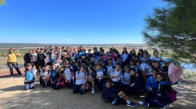 Alumnos de 6.º de Primaria posan juntos bajo los pinos, con el paisaje de Castronuño al fondo.