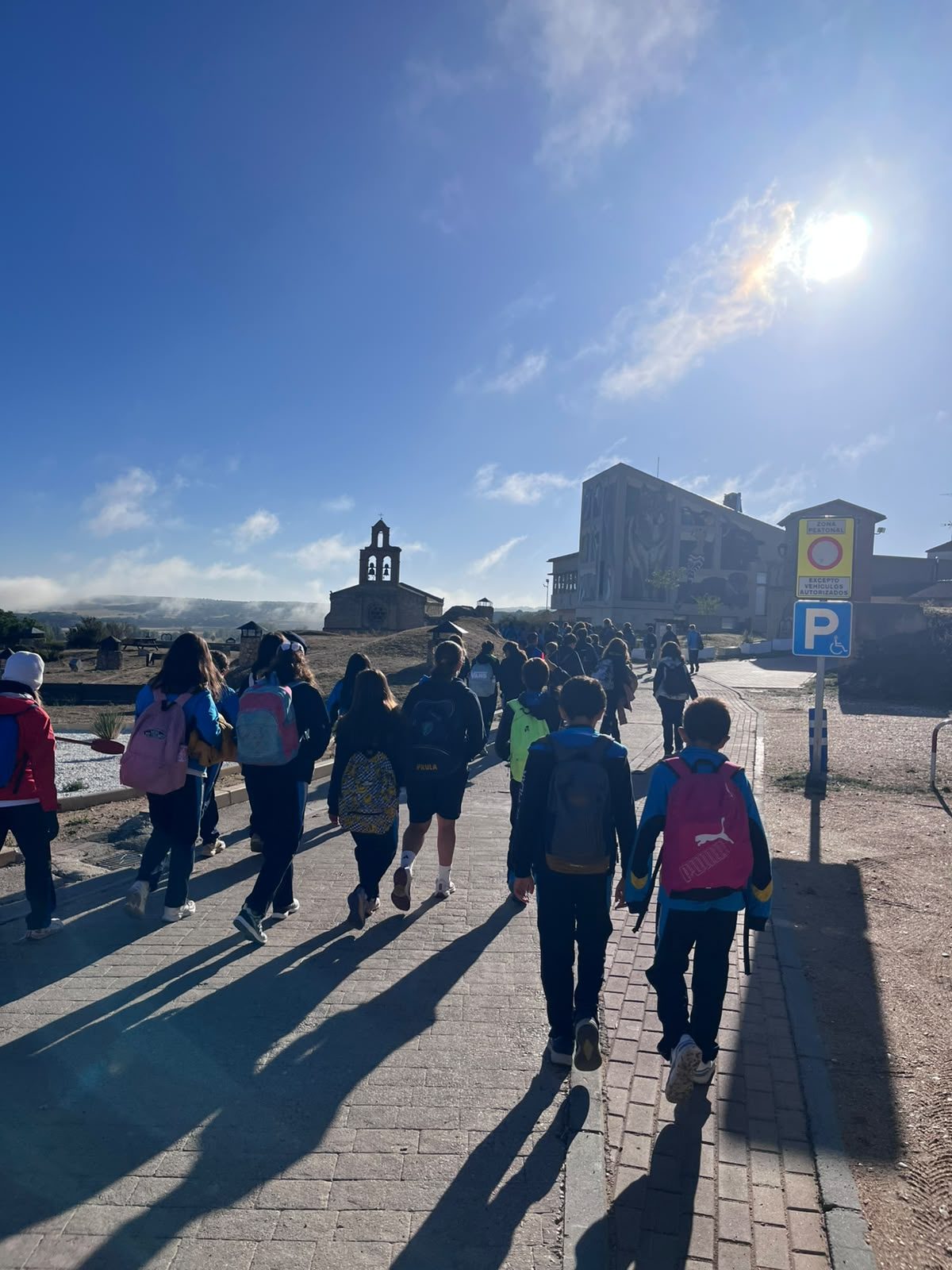 El grupo de 6.º de Primaria avanza con sus mochilas por una calle de Castronuño bajo el sol.