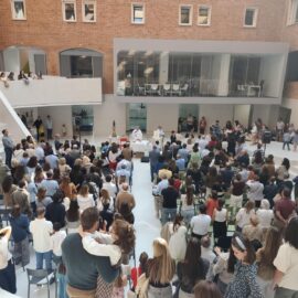 Niños y adultos permanecen de pie alrededor del altar durante la eucaristía, en un espacio con gradas.