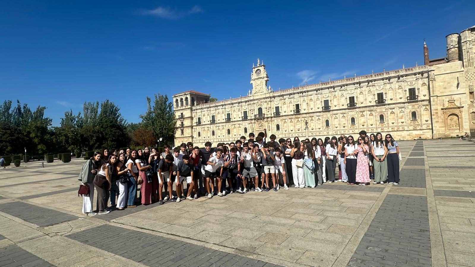 El grupo de alumnos posa en una amplia plaza frente al Parador de San Marcos, bajo un cielo despejado.