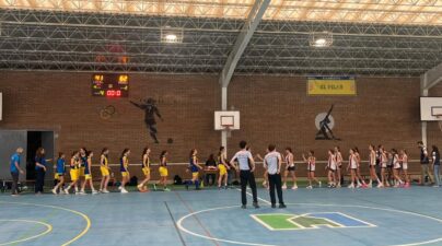 Jugadoras de ambos equipos se acercan para saludarse en la pista cubierta, con dos árbitros en primer plano.
