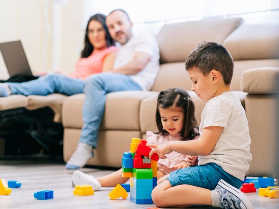 family-in-the-living-room-parents-telework-with-the-computer-and-children-play-on-the-floor