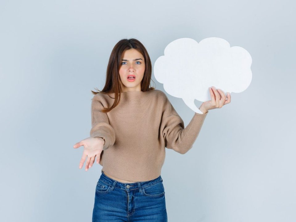 young-woman-in-sweater-jeans-being-displeased-with-dumb-question-keeping-paper-speech-bubble-and-looking-gloomy-front-view (1)